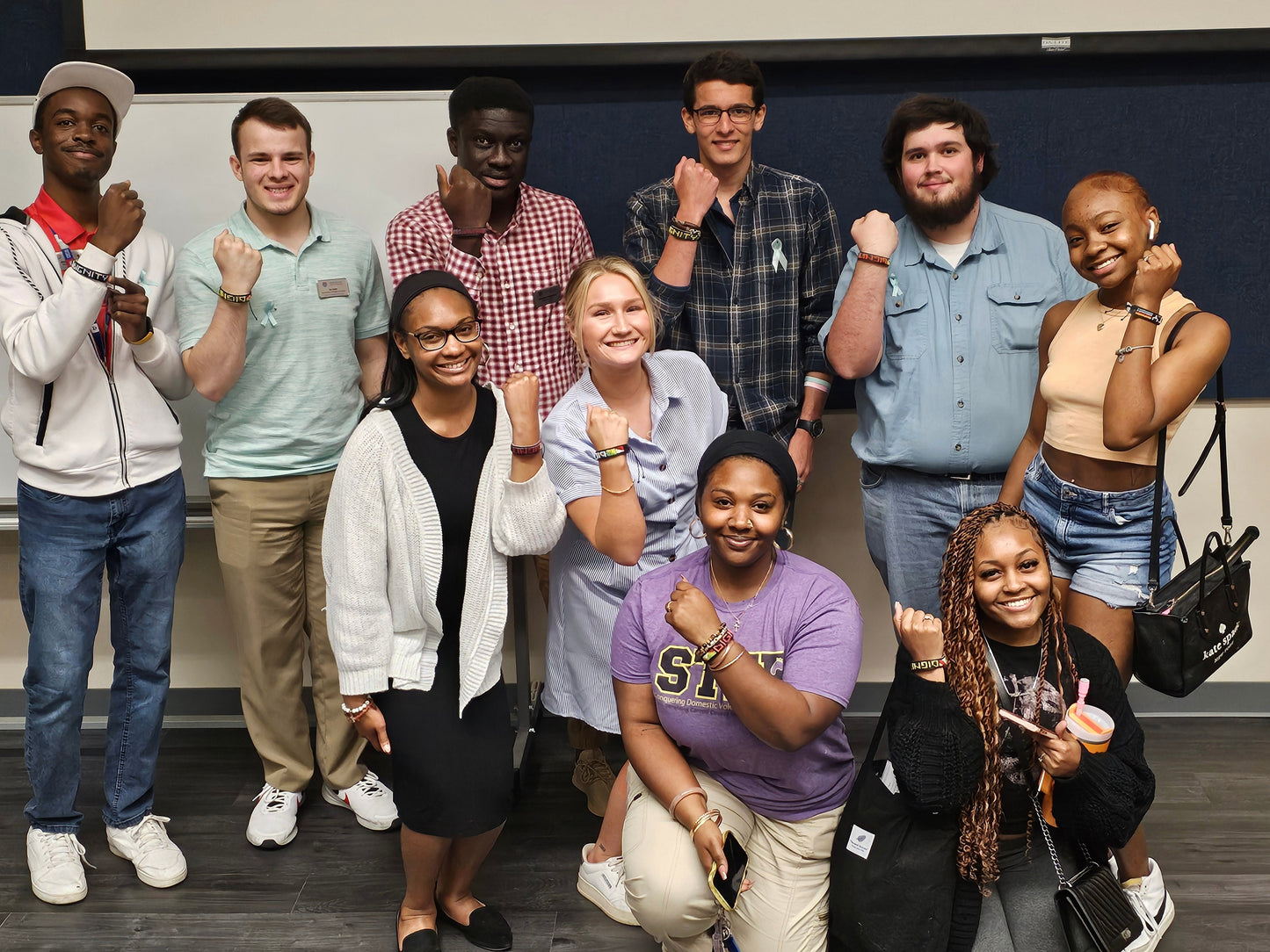Group of young adults posing together in a classroom setting